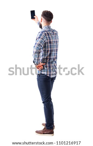Back view of adult man taking photo or selfie with smartphone. Full body isolated on white background.