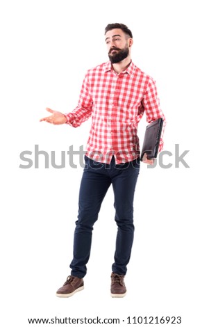 Confused young adult bearded business man with laptop under arms shrugging and looking away. Full body isolated on white background.