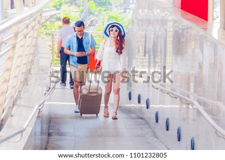 Young asian couple are walking with holding backpacker in city. A man holding briefcase.They are walking on staircase. Photo Asian tourisms and vacation in Bangkok concept.
