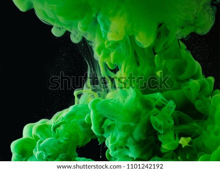close-up view of green abstract flowing paint on black background    