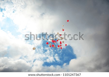 Many colorful bright balloons flying in the air in the sky with clouds