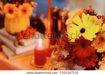 Autumn wedding decoration with flower composition with roses, chrysanthemum, maple leaves, pumpkin, books and candles. Haloween concept