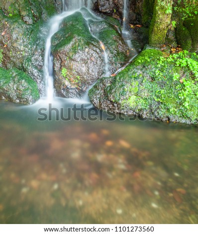 Small silky water fall running over moss covered rocks.