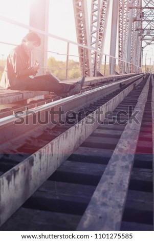 A man with an electric guitar on the railway. A musician in a leather jacket with a guitar on the street in the industrial zone. Guitarist on the bridge.
