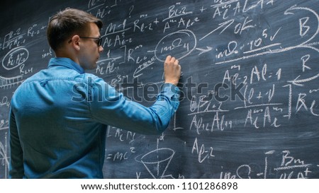 Brilliant Young Mathematician Approaches Big Blackboard and Finishes writing Sophisticated Mathematical Formula/ Equation. Royalty-Free Stock Photo #1101286898