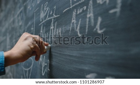 Close-up Shot of a Hand Holding Chalk and Writing Complex and Sophisticated Mathematical Formula/ Equation on the Blackboard. Royalty-Free Stock Photo #1101286907