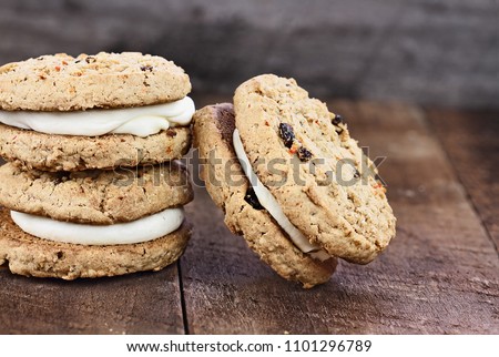Carrot cake raising cookie sandwiches stuffed with cream cheese icing against a rustic wooden background. Room for copy text.