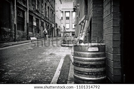 A black and white analogue image of a lonely figure walking down an old alleyway in Glasgow town center