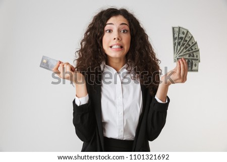 Photo of emotional young business woman with credit card and money isolated over white wall backgound.