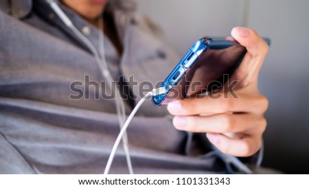 A man listening to music in earphones on his smartphone.