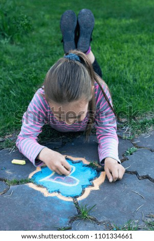 front view from above of a girl on the draws  on the sidewalk in the summer garden