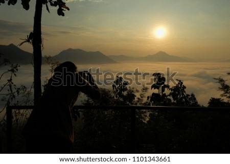 Silhouette of a female taking a picture with the sunrise background at morning.
