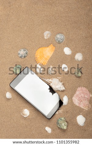 Smartphone on sea sand with seashells. Top view with copy space