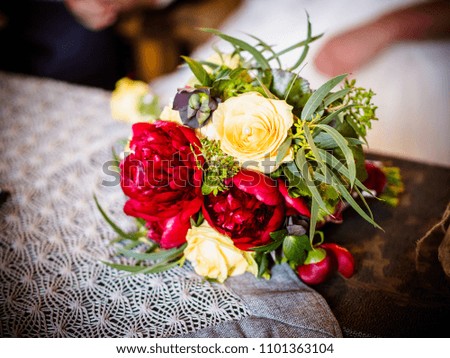 The bride is holding a chic wedding bouquet of roses and peonies, on the car red roses and peonies