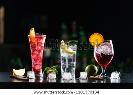Multi-colored alcoholic cocktails with citrus in glasses of different shapes on the bar.