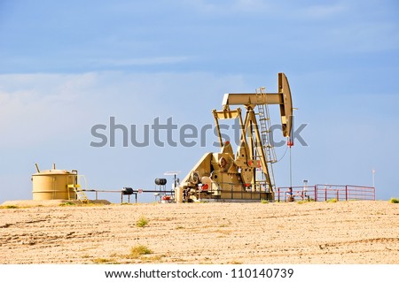 Low view of a working oil pump jack pumping crude.