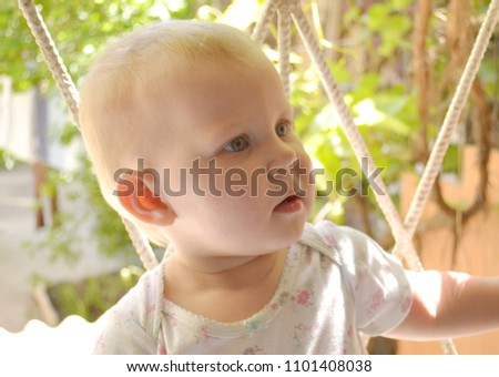 The baby is standing on the window. Portrait of a child standing on a windowsill. Window and infant.