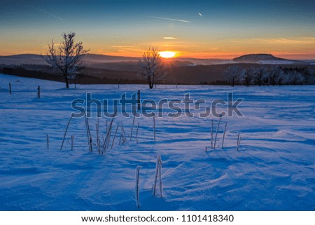 Sunset in the golden sunlight over the winterly Ore Mountains. View to the mountain "Scheibenberg", mountain "Fichtelberg" and mountain "Keilberg"