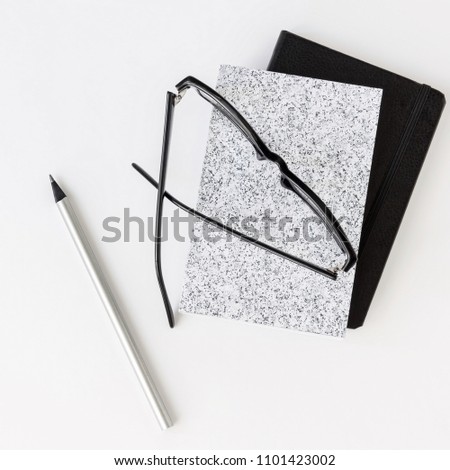 Notebooks, eyeglasses and pen on white desk