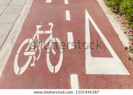 Bike lane. Bicycle sign and white directional arrow on red asphalt path