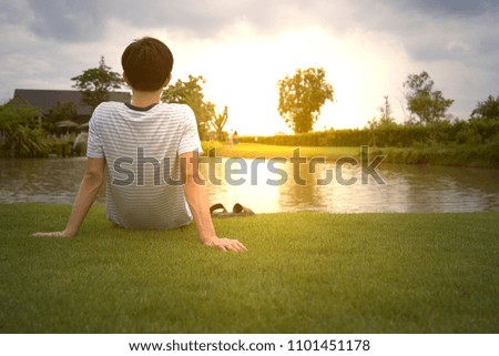 Asian young man sitting by the pool watching the sunset.