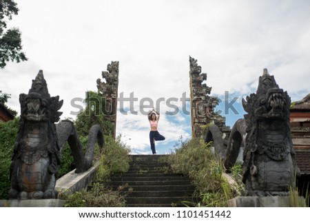 Woman staying in yoge pose at old stone stairs temple entrance balinesse gate