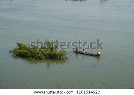 Two women and a child sitting in a traditional boat on a lake in Laos, shot from above