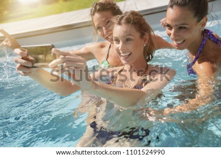 Girls in outdoor swimming-pool taking selfie pictures