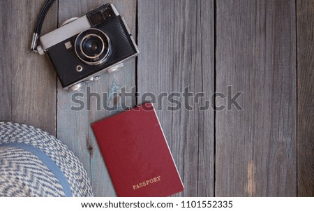 A hat, an old camera and a passport on wooden background