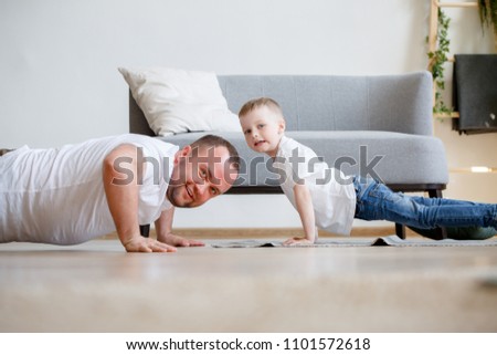 Photo of happy dad and son pushing on floor