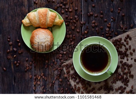 Cup of coffee with croissant on wooden background