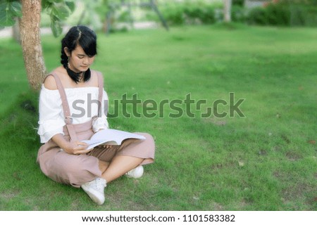 the asian girl's sitting in the park and reading a book on the  day