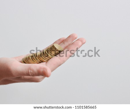 A tall hand of a men holding money, golden coins, on white background, isolated, side view, copy space