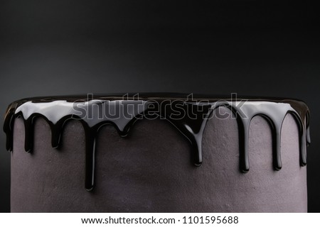 Chocolate cake with black glaze on a black background. Picture for a menu or a confectionery catalog.