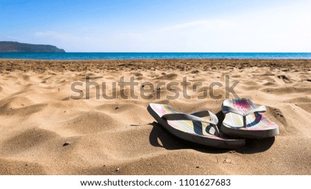 Colorful flip flop sandals on the sandy beach in Crete, Greece.
