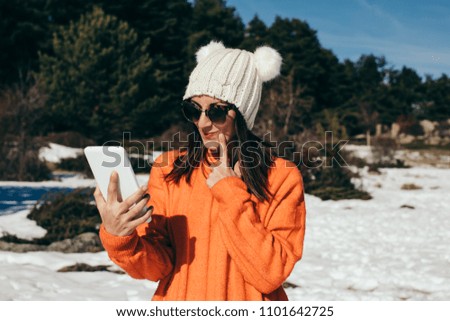 Young and cheerful woman using her tablet, to stay connected with her family, on the mountain a day of snow and sun. Lifestyle.