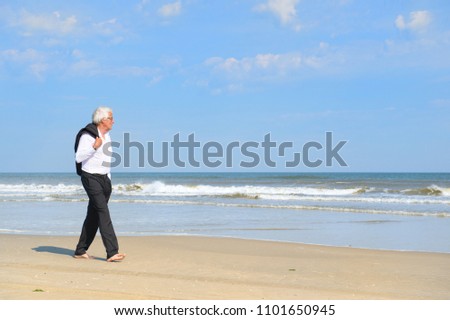 Business man in formal suit walking at the beach