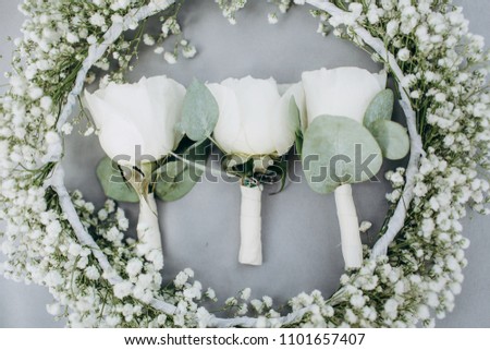 Three white roses 
boutonnieres and wreath of flowers on grey background
