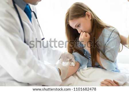 Male Doctor a pediatrician makes child vaccinated vaccination in medical office