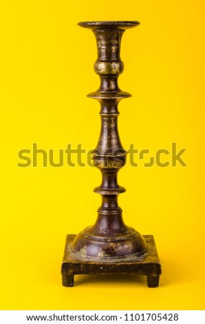Vintage bronze candlestick on yellow background. Studio Photo