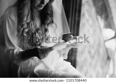 Wedding day. Room in style of Morocco. The bride sits at window and reads letter to groom. Wedding vows. Morning of the bride. Dress with lace. Black and white photo