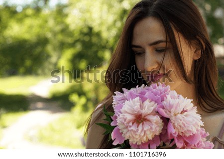 Pretty young beautiful woman on a bench with peony flowers and shining sun. Place for text	
