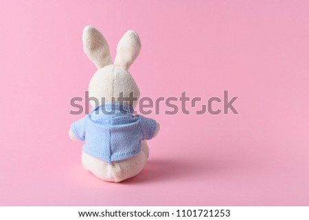 White rabbit doll on a pink background. Minimal concept.