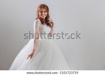 Lovely young woman bride in a lavish wedding dress. Light background.