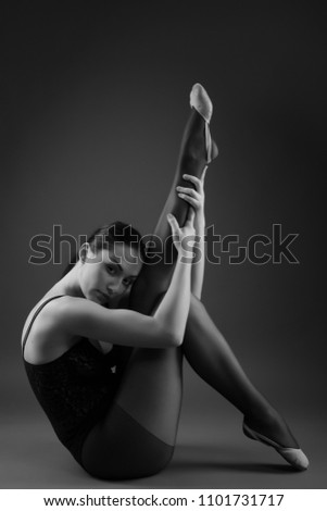 Flexible ballet dancer stretching in the dark lighted studio