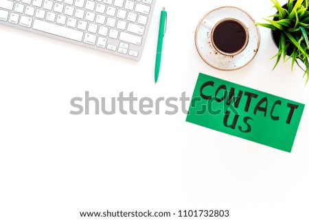 Frame contact us. Lettering Contact us on office work desk with computer on white background top view copy space