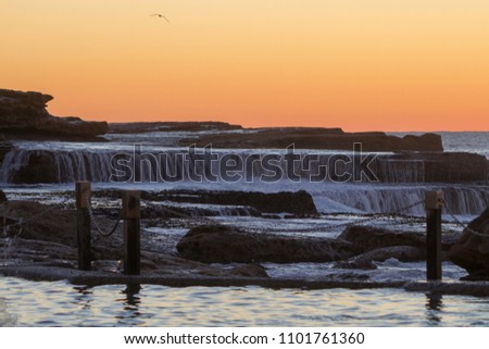 Slow motion waves flowing over rocks as the sun rises over the ocean