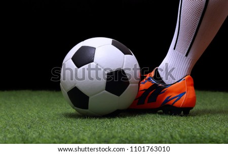 close up legs and feet of soccer player or football player walk on green grass ready to play match on black background.