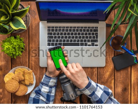 person scrolling news at smartphone with chroma key on a wooden table