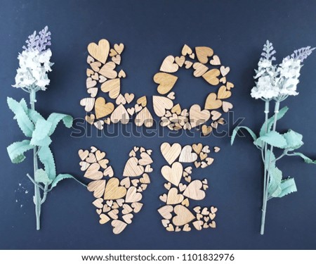 LOVE word on dark background with artificial flower, an arrangement of the love shape of wood pieces ( selective focus) 